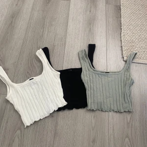4 ribbade croppade linne-toppar XS Shein - Fyra croppade linne-toppar från Shein i storlek XS. En vit, en svart, en grå och en ljusgrön, alla med ribbad struktur och breda axelband. Perfekt för att styla med jeans eller kjol. Snygg vågig kant nedtill ger en extra touch. 60 kr för alla 