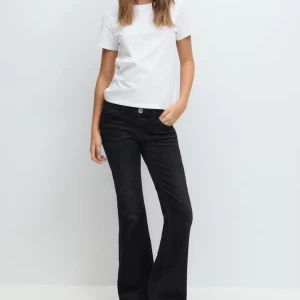 Svarta bootcut jeans 170 storlek  - Snygga svarta jeans med bootcut passform och broderade detaljer på bakfickorna. Jeansen har klassisk femficksdesign, normal midja och är tillverkade i ett mjukt denimtyg. Perfekta för dig som gillar en stilren look med lite edge. Storlek 170 barn från Gina Young.