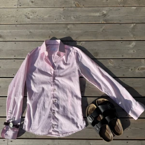 Ljusrosa skjorta från Eton, slim fit - Säljer en stilren ljusrosa skjorta från Eton i storlek 38, super slim fit. Nypris ligger på 1700kr. Skjortan har klassisk krage, knäppning framtill och långa ärmar. Tillverkad i 100% bomull som känns skön mot huden. Perfekt för dig som gillar en clean och fräsch look.