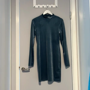 Blå klänning  - Snygg blå sammetsklänning från H&M i storlek M. Klänningen har lång ärm, rak passform och hög hals. Materialet är mjukt och glansigt, vilket ger en lyxig känsla. Perfekt för dig som gillar stilrena och enkla plagg med lite extra shine. Perfekt till höst och vinter! Använd få gånger