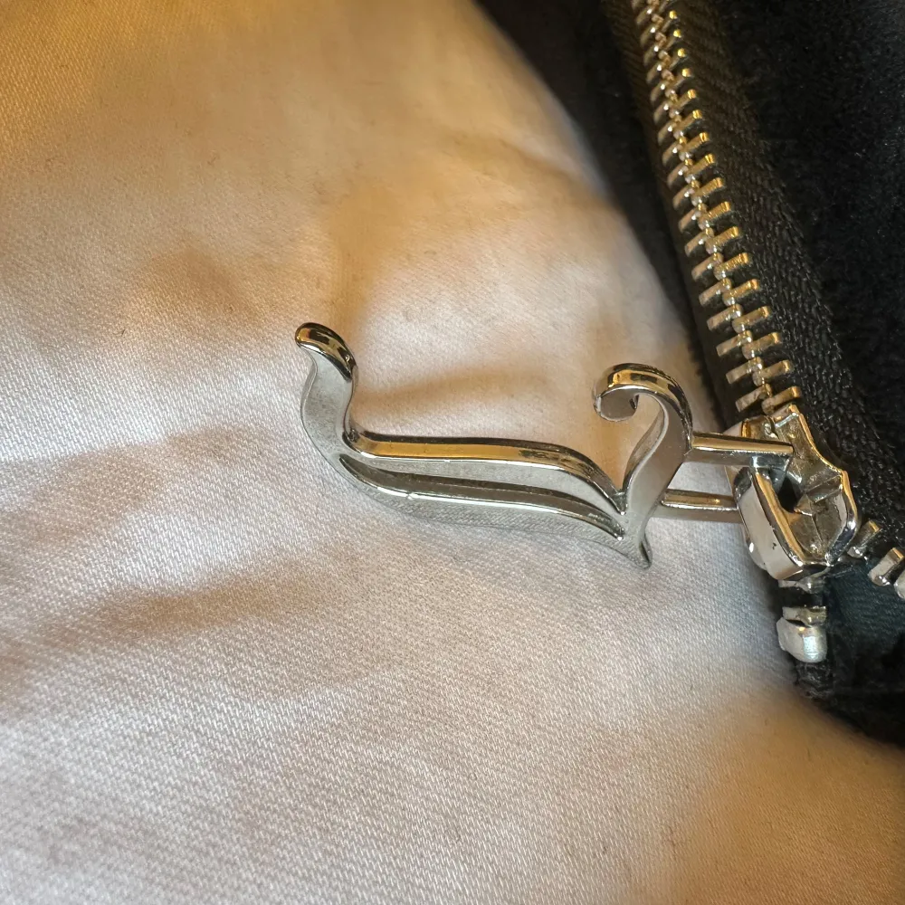 Snygg svart axelväska från Juicy Couture i mjukt material. Väskan har en dragkedja upptill och ett stilrent märke på framsidan. Perfekt för att bära dina nödvändigheter med stil.. Laukut & Käsilaukut.