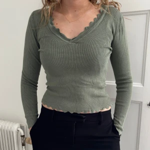 Grön ribbad topp från JDY - Säljer en grön ribbad topp från JDY med v-ringad hals och vågiga kanter💞💞