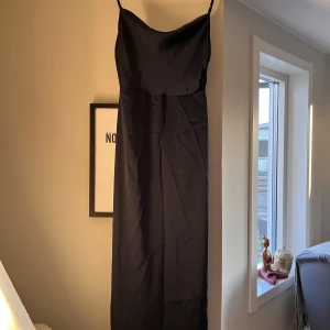 Mörkblå långklänning från VILA - Elegant mörkblå långklänning från VILA med smala axelband. Perfekt för en stilren look. Klänningen har en enkel och tidlös design som passar många tillfällen.