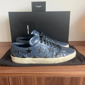 Skor från Saint Laurent - Snygga blå sneakers från Saint Laurent med svarta stjärnor som dekoration. Skorna har en rund tå och klassisk snörning. Perfekta för en stilren look. Riktigt feta och unika skor! PRIS KAN DISKUTERAS! Storlek 42 men passar 43