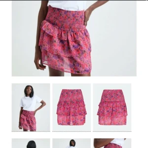 Blommig kortkjol med volanger - Säljer en färgglad blommig kortkjol med volanger. Kjolen har en elastisk midja och är perfekt för sommarens varma dagar. Den har ett livfullt mönster i rosa och lila toner.