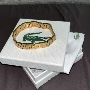 Guldarmband från Lacoste - Helt ny och aldrig använt. Den har länkar som man kan ta bort för att ändra storleken beroende på vad som passar dig. För frågor eller förhandling skriv till mig. 