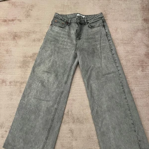 Grå wide jeans från NA-KD - Säljer ett par grå wide jeans från NA-KD. De har en klassisk femficksdesign och är tillverkade i ett slitstarkt material. Perfekta för en avslappnad stil.