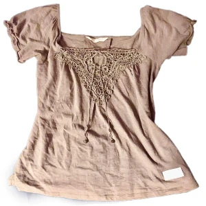 Vacker Odd Molly topp - Säljer en söt beige topp med korta ärmar och vacker spetsdetalj framtill. Toppen har en knytning vid halsen och en fyrkantig urringning. Perfekt för en avslappnad stil. Passar både S och M.