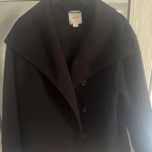 Svart kappa från Marimekko - Elegant svart kappa från Gina tricot Young med stora slag och knappar framtill. I storlek 158/164. 