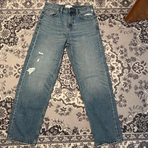 Blå baggy jeans från ASOS Design - Säljer ett par blå baggy jeans från ASOS Design. De har en avslappnad passform med slitna detaljer för en trendig look. Perfekta för en casual stil.