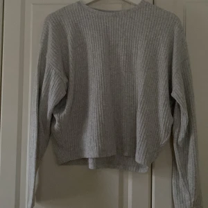 Grå ribbad tröja från H&M - Säljer en stilren grå ribbad tröja från H&M. Tröjan har en avslappnad passform med långa ärmar och rund halsringning. Perfekt för en mysig dag hemma eller en avslappnad dag ute. Skicka ett meddelande vid intresse!