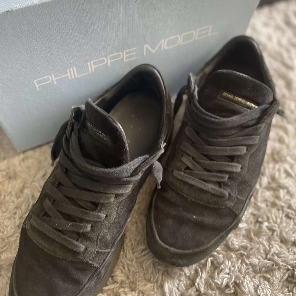 Snygga svarta sneakers från Philippe Model i mocka. Skorna har en klassisk design med snörning och en rund tå. Perfekta för en stilren look.. Kengät.