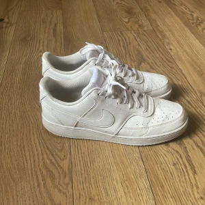 Vita Nike skor  - Säljer ett par stilrena vita sneakers från Nike. Skorna har en klassisk design med snörning och rund tå. Perfekta för en avslappnad look.