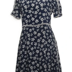 Blommig klänning från The Kooples i Siden - Snygg marinblå klänning från The Kooples med vita blommor. Den har korta ärmar och en fin detalj med små bollar längs kanterna. Perfekt för en somrig look!