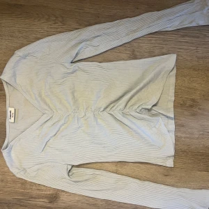 Ljusblå randig topp från Kappahl - Säljer en ljusblå långärmad topp från Kappahl med smala ränder och en snygg rynkdetalj framtill. Perfekt för en stilren look. Endast använd några fåtal gånger. Super fin till vardags men även vid lite festligare tillfällen!💙