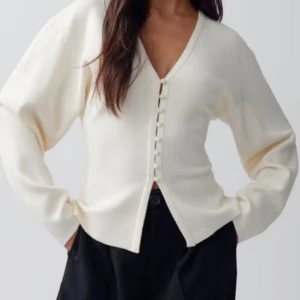 Vit kofta med knappar - Säljer en stilren vit kofta med v-ringning och dekorativa knappar framtill. Perfekt för en elegant och avslappnad look. Passar bra till både jeans och kjol.