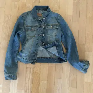Snygg blå jeansjacka från Zoul. Jackan har långa ärmar och knappar framtill samt två bröstfickor. Storlek S Passar mig som är 164cm 