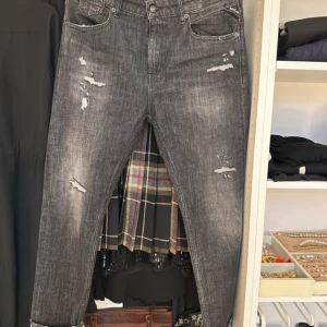 Grå jeans med slitningar från Replay - Snygga grå jeans från Replay  med slitningar för en trendig look. De har en slim fit passform och är tillverkade i ett bekvämt material.