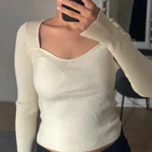 Beige ribbad topp - Säljer en stilren beige ribbad topp med långärmad design. Toppen har en unik skärning vid halsen som ger en modern touch.