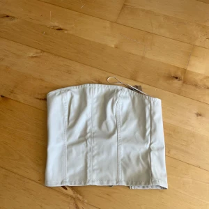 Vit korsett  - Snygg vit korsett från Bershka. Den har en dragkedja baktill för enkel på- och avtagning. Perfekt för att ge en trendig touch till din outfit.