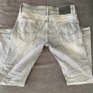 Grå jeans från Jack & Jones - Säljer mina Gråa Slim Glenn då dom har blivit för korta för mig. Dom är i storlek 29 30 och är i bra skick, använt sparsamt. Stilrena och passar till allt. Skriv vid minsta fundering :)