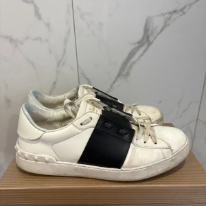 Valentino sneakers i vitt och svart - Snygga Valentino sneakers i vitt med en bred svart rem över snörningen. Skorna har en rund tå och är perfekta för en stilren look. De är tillverkade i skinn och har en klassisk design som passar till många tillfällen. Pris kan diskuterar ej ristat i sten 🪨 ✅