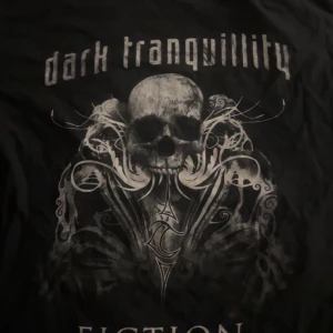 Svart t-shirt med tryck från Gildan - Cool svart t-shirt från Gildan med tryck av en dödskalle och texten 'dark tranquillity' och 'THE ULTIMATE REBELLION'. Perfekt för dig som gillar rockig stil. Tillverkad i bomull för en skön känsla. #rocknroll #fashion #plick #oversize 
