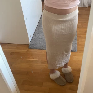 Beige ribbad kjol från Amisu - Säljer en stilren beige ribbad kjol från Amisu. Kjolen är lång och har en smickrande passform med en liten slits på sidan. Perfekt för en chic och avslappnad look. Går längre inte att köpa i butik. 
