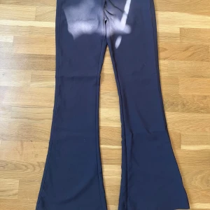 Kostymbyxor - Snygga svarta byxor från Gina Tricot med bootcut-stil. Byxorna har en dragkedja och knappar framtill samt fickor med knappar bak. Perfekta för en stilren look.