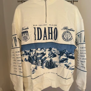 Ny, oanvänd, häftig sweatshirt från Bershka! - Ny, oanvänd, häftig vit sweatshirt med blått tryck från Bershka med prislappen kvar i storlek XS. Sweatshirten har en hög krage med dragkedja, ett retro uttryck och lös passform.