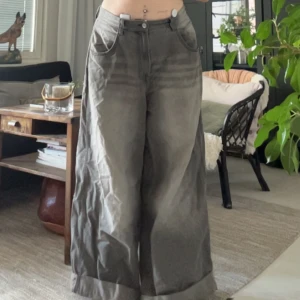 Grå wide cargopants från Bershka - Säljer ett par grå cargopants från Bershka med bred passform och hög midja. Byxorna har stora bakfickor, broderad Pure Oil-logga och är tillverkade i bomull. Healbites på, har vikt upp dom längst ner då dom är väldigt långa annars.  Är 170cm och dom är nästan lite korta för mig. Skriv gärna om ni har frågor!💕