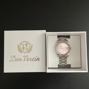 Seiko Mod med rosa urtavla - Seiko Mod med silverfärgad länk och en snygg rosa urtavla. Klockan har klassisk rund form, datumvisning och levereras i originalask. Perfekt accessoar för dig som vill sticka ut med en elegant touch.