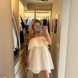 Vit volangklänning H&M - Superfin vit kort klänning med tunna band över axlarna från H&M med volang upptill. Klänningen är luftig och har en lätt skrynklig struktur i tyget. Säljs i storlek 36 och är riktigt söt och trendig.