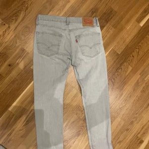 Levi's 512 ljusgrå jeans - Säljer ett par Levi's 512 jeans i en snygg ljusgrå tvätt. Modellen har klassiska fem fickor, raka ben och normal passform. Jeansen har den ikoniska läderpatchen bak och är tillverkade i mjukt bomullsjeans-tyg. Perfekta för en clean och stilren look.