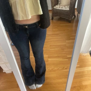 True Religion Joey flare jeans blå - Snygga mörkblå jeans från True Religion, modell Joey Low Rise Flare. Klassisk femficksdesign med utställda ben och låg midja. Tuffa detaljer på bakfickorna och kontrastsömmar. Perfekta för dig som gillar retrovibbar och statement-jeans.