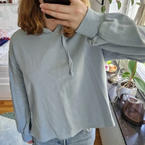 Ljusblå hoodie - Mysig ljusblå hoodie med gulddetaljer och slits på sidorna. Från Pernilla Wahlgrens kollektion och är knappt använd