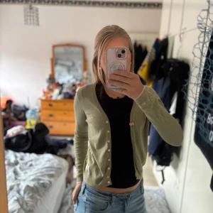 Ljus grön kofta  - Olivgrön cardigan från Odd Molly med långa ärmar, knappar framtill och små rosa detaljer som broderad logga och rosett. Liten lapp nertill och rosa kant vid ärmslut. Perfekt med ett linne eller T-shirt under 💕 pris kan alltid diskuteras, köpte för runt 670kr 