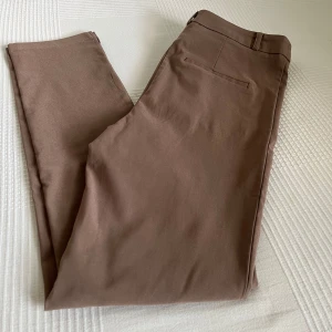 Beige slim kostymbyxa med fickor - Ett par snygga kostymbyxor i en beige färg från Bubbelroom. Kostymbyxorna har en tight passform samtidigt som dem är relativt stretchiga. Kostymbyxorna har hög midja. Exakta modellen på byxorna är (Artikel nummer: 710518). Dessa är aldrig använda. Prislappen är dock inte kvar. Säljer då dessa är för stora för mig. 