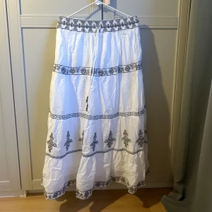 Vit långkjol med broderade detaljer - Supersnygg vit långkjol med svarta broderade mönster och snörning i midjan💖💖