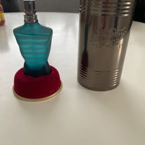 Jean Paul Gaultier Le Male 40ml - Ikonisk parfymflaska i form av en blågrön, randig manlig torso. Flaskan är frostad glas med turkosa och ljusblå ränder. Kommer med original metallburk och röd sammetsbas. Eau de toilette, 40 ml.