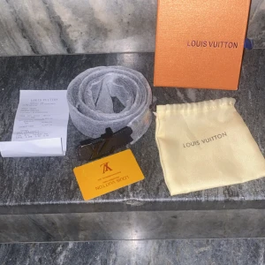 Brunt Louis Vuitton skärp med LV-spänne - Säljer ett brunt Louis Vuitton bälte i skinn med klassiskt LV-spänne i mörk metall. Bältet har en stilren och tidlös design, perfekt för att lyfta vilken outfit som helst. Levereras med originalbox, dustbag och kvitto. Priset kan diskuteras vid snabb affär.