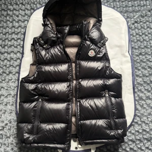 Moncler väst - Säljer min Moncler-väst då den inte kommer till användning längre. Den är i fint skick, sparsamt använd och har mest hängt i garderoben. Väldigt snygg och passar perfekt till både höst och vår. Inga skador eller fläckar.