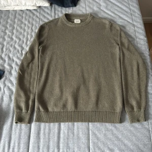 Olivgrön stickad tröja från Dobber - Säljer en olivgrön stickad tröja från Dobber i storlek medium. Tröjan har rund halsringning, ribbade muddar och nederkant. Perfekt för dig som gillar en enkel och stilren look med en touch av street.