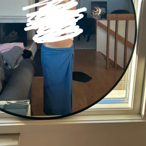 Blå långkjol med omlottknyt - Säljer en blå långkjol med omlottknyt i midjan. Kjolen har en enkel och stilren design, perfekt för dig som gillar en avslappnad men ändå snygg look. Färgen är klassiskt blå och modellen är rak och lång. Från vila 