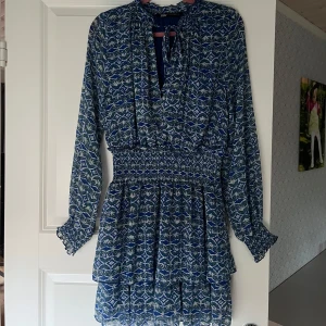 Blåmönstrad kortklänning från Zara XS - Supersöt blå kortklänning från Zara i storlek XS. Klänningen är sparsamt använd och i jättefint skick! Finns knytning  vid halsen och resor i midjan🥰