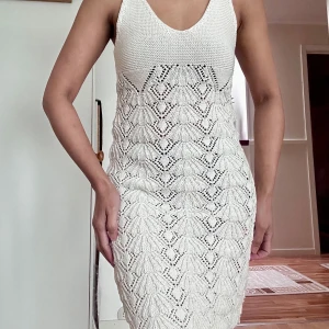 Knitted summer dress - Supersnygg vit stickad klänning från Bershka med v-ringning och ärmlös design. Klänningen har ett unikt mönster med virkade detaljer och sitter figurnära. Perfekt för sommarens alla tillfällen och ger en fräsch och trendig look.
