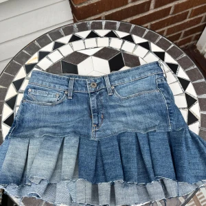 Levi's plisserad jeanskjol blå - Säljer en blå jeanskjol från Levi's med plisserad nederdel och rå kant. Kjolen har klassiska femficksdetaljer, knapp och dragkedja framtill samt Levi's-logga bak. Perfekt för dig som gillar en cool och avslappnad stil. Jag har sytt denna jeanskjolen själv💗😝