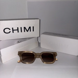 Beige CHIMI solglasögon Ecru 04 - Snygga solglasögon från CHIMI i modellen Ecru 04. De har en fyrkantig form med transparent beige båge och bruna glas. Perfekta för dig som vill ha en clean och modern look. Kommer med originaletui och box.