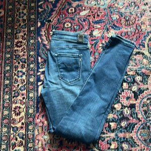 Blå Replay jeans - Snygga blå jeans från Replay med klassisk femficksdesign och slim passform. Jeansen har en mörkblå tvätt och detaljerade sömmar på bakfickorna. Perfekta för dig som gillar en modern look.