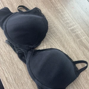 Svart push-up bh med spetsdetaljer - Svart push-up bh från ESMARA med tunna axelband och fina spetsdetaljer längs kuporna. Bh:n har vadderade kupor och justerbara axelband för bästa passform. Klassisk och stilren design som passar till det mesta.